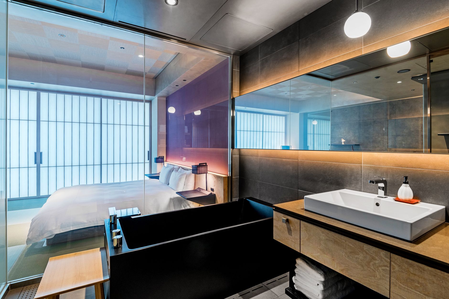 Salle de bain d'hôtel élégante avec une porte vitrée donnant sur une chambre élégante, présentant des intérieurs luxueux.