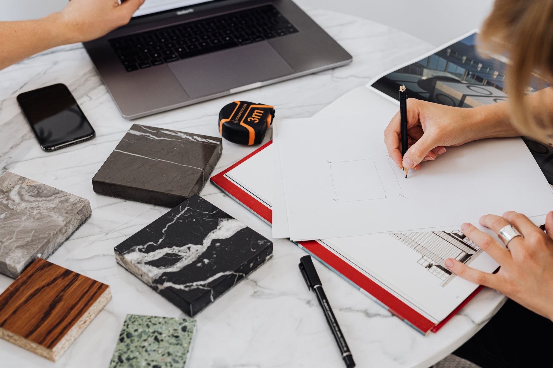 Un espace de travail montrant le processus de conception architecturale avec des échantillons de matériaux et des dessins.