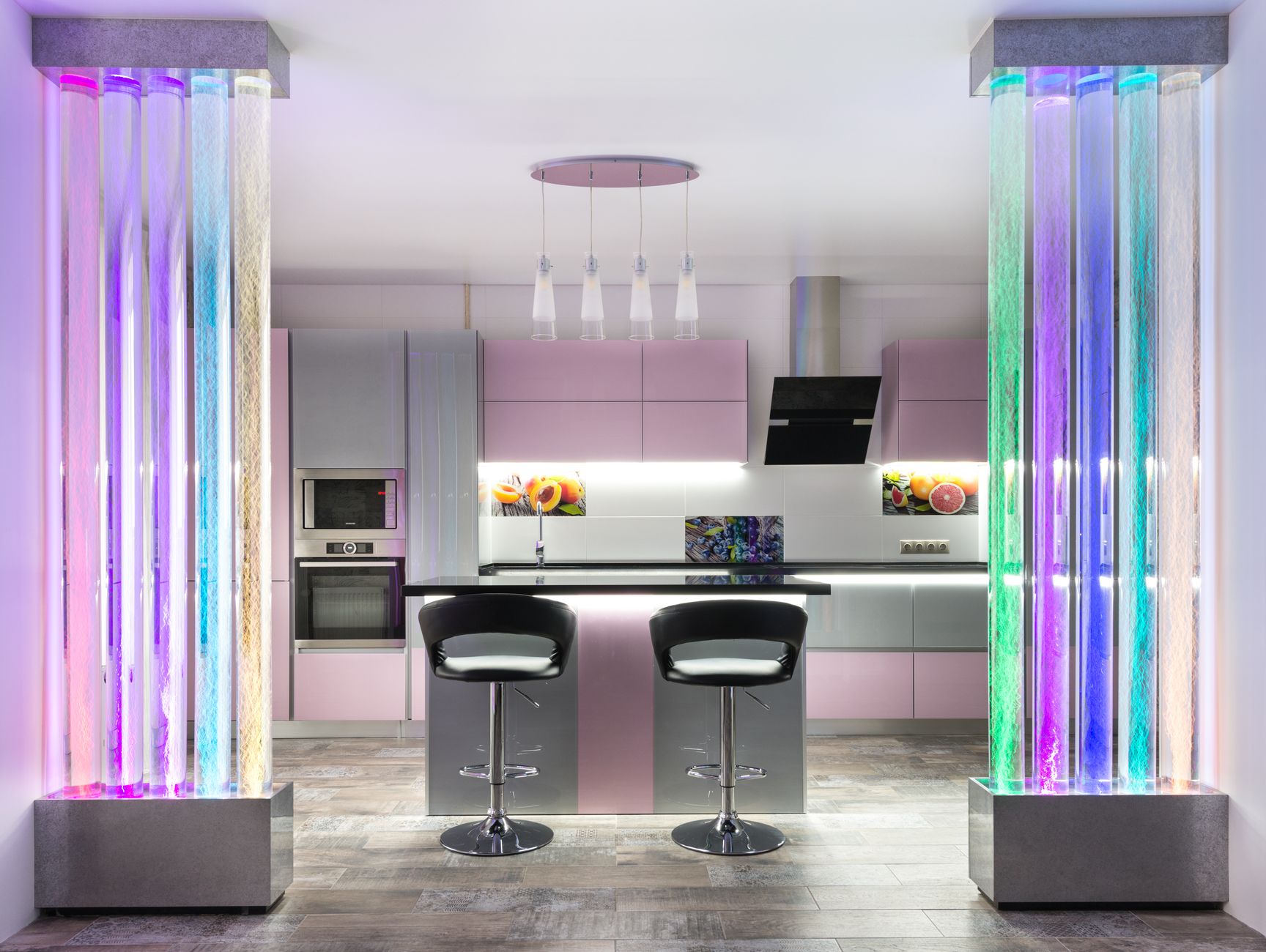 Intérieur d'une cuisine contemporaine avec table et chaises placées près de placards colorés avec de la vaisselle moderne dans un appartement élégant avec des murs décoratifs à bulles vives